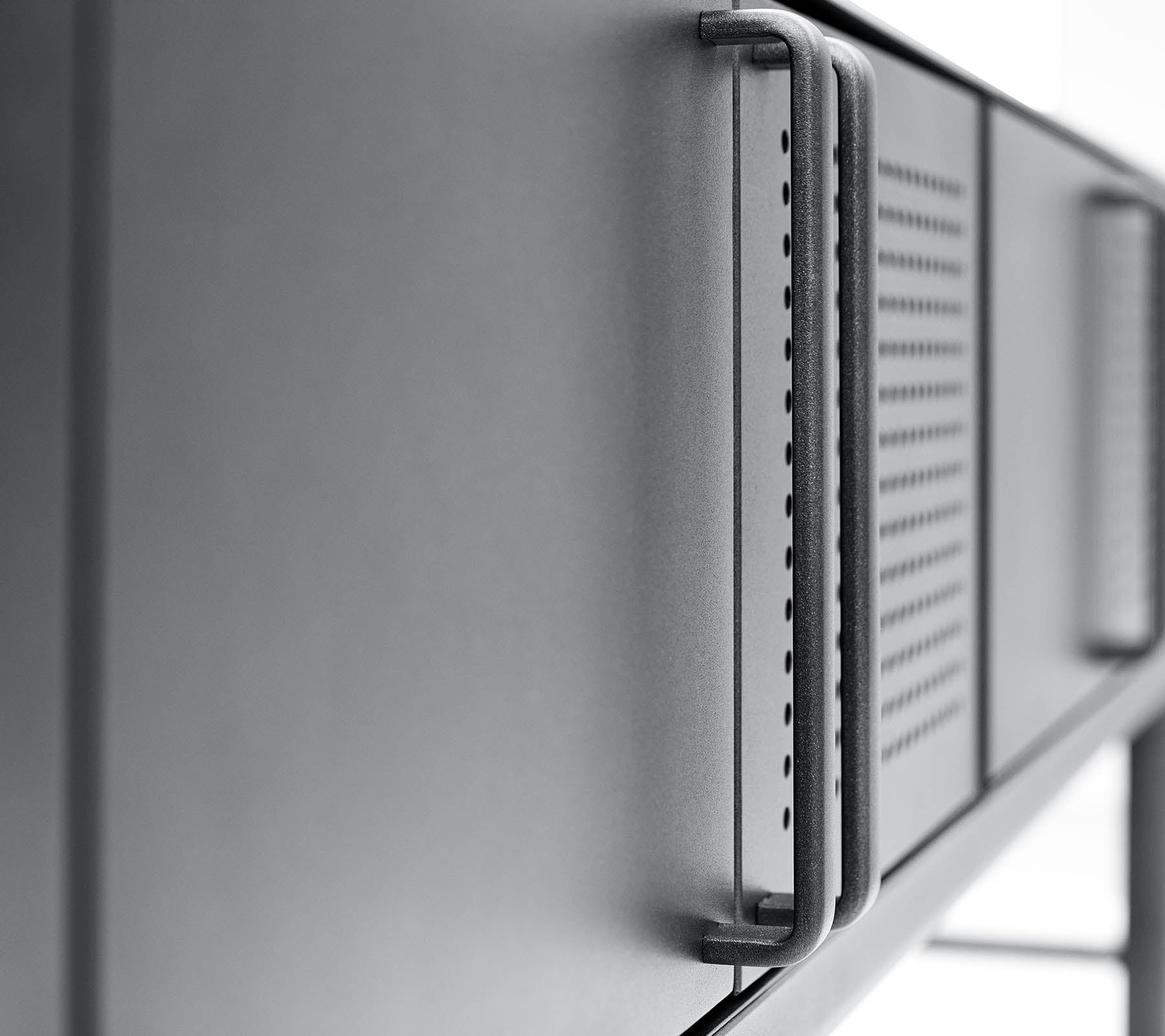 Close-up van een slanke, moderne metalen oppervlakte met een handgreep en ventilatiedetails, die een minimalistisch design benadrukken.