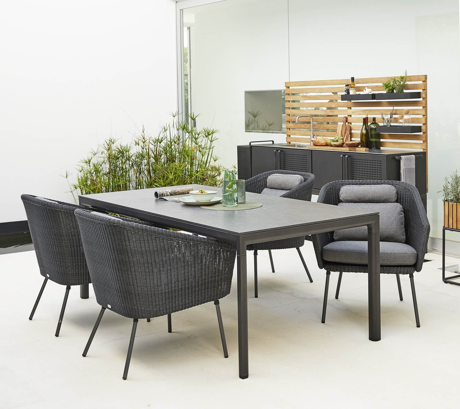 Stijlvolle buitentafelset met een slank tafel en comfortabele, moderne stoelen omringd door decoratief groen.
