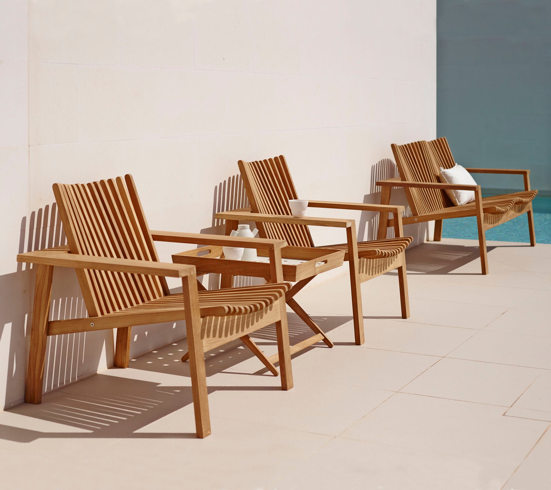 Drie houten ligstoelen met lattenontwerpen in een rij, met een eenvoudige, elegante stijl die geschikt is voor ontspanning.