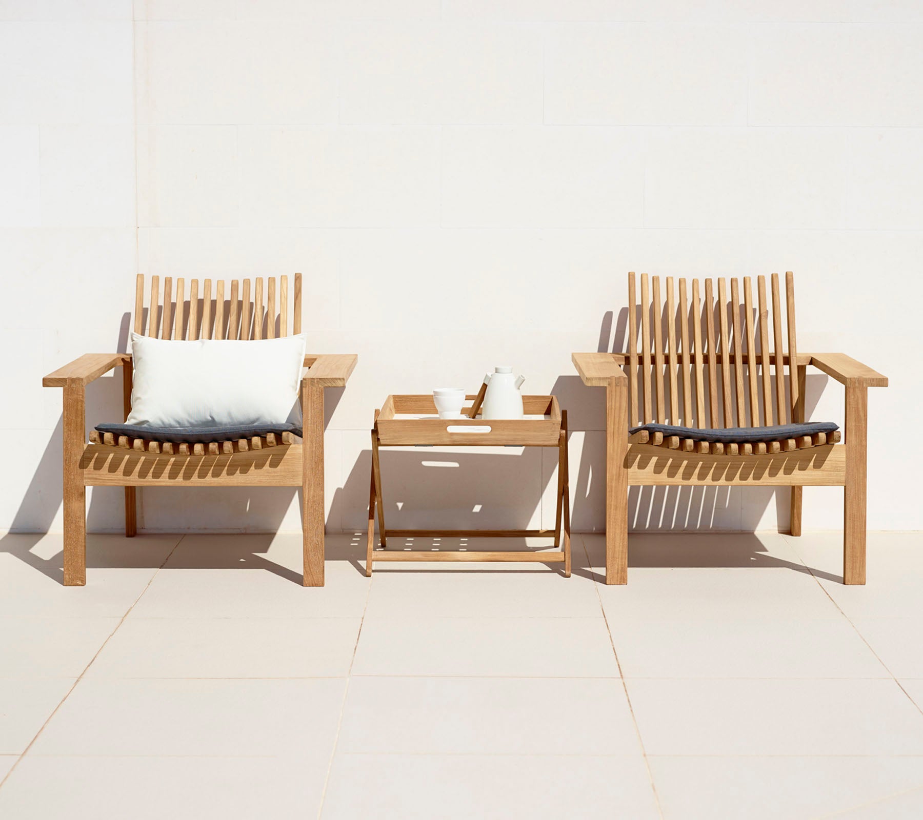 Twee stijlvolle houten stoelen met kussens en een klein side-table, die een gezellige zithoek creëren.