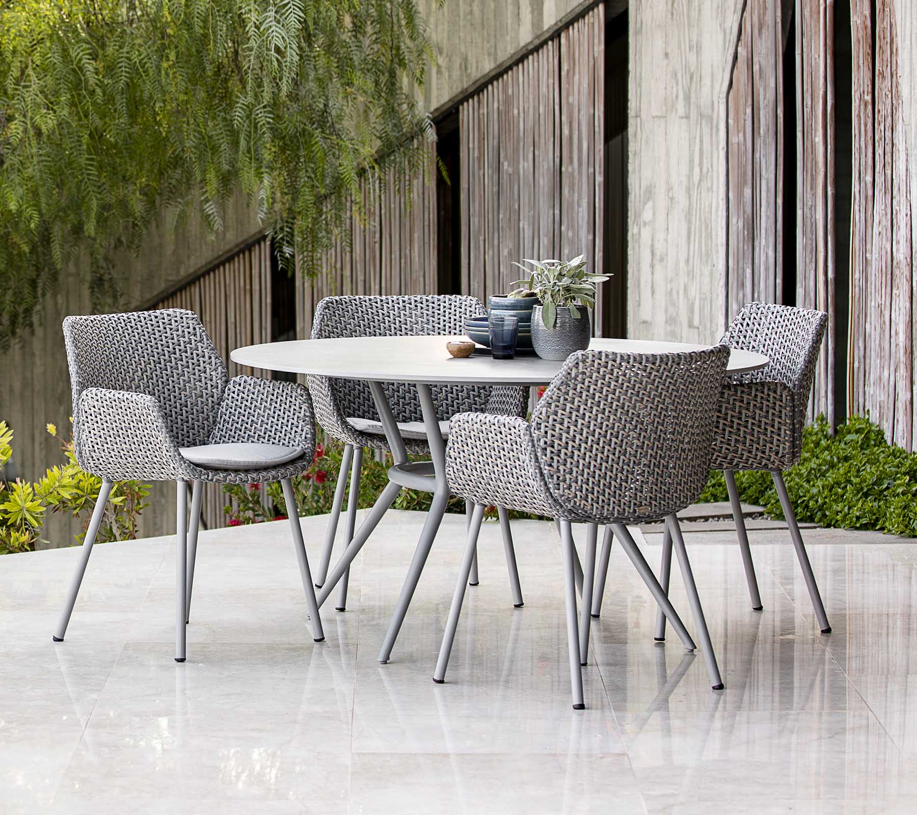 Tijdloze buitentafelset met gevlochten stoelen, gestyled met planten en tafeldecoratie, met een moderne esthetiek.