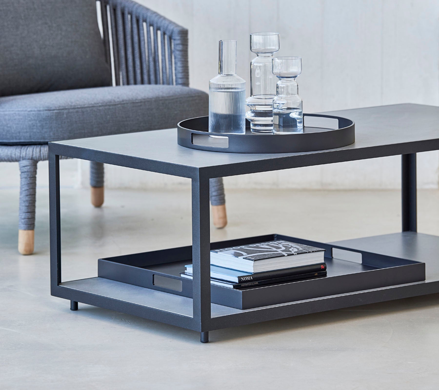 Modern salontafel met een strak design, met een dienblad, glazen en boeken op de onderste plank. Ideaal voor stijlvolle woonruimtes.