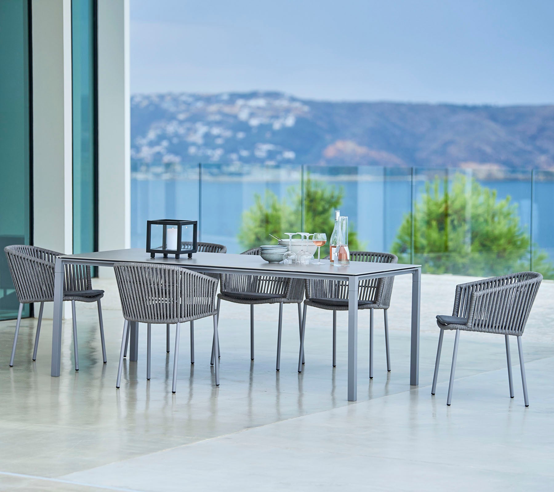 Elegante buiten eetset met een rechthoekige tafel en stijlvolle gevlochten stoelen met een panoramisch uitzicht op de achtergrond.