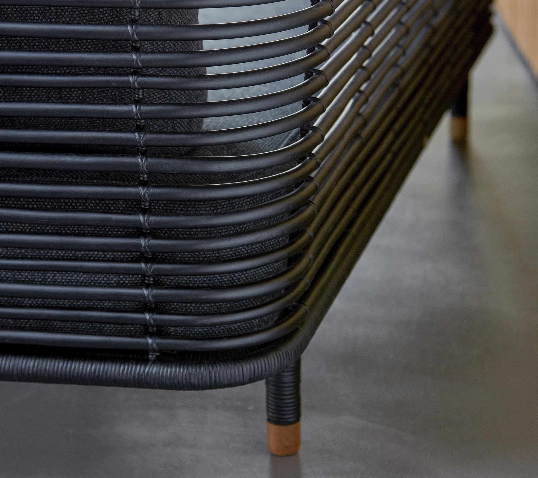 Stijlvol zwart geweven meubilair met gebogen lijnen en houten accenten, dat een moderne ontwerpesthetiek laat zien. Een perfecte aanvulling op elke ruimte.