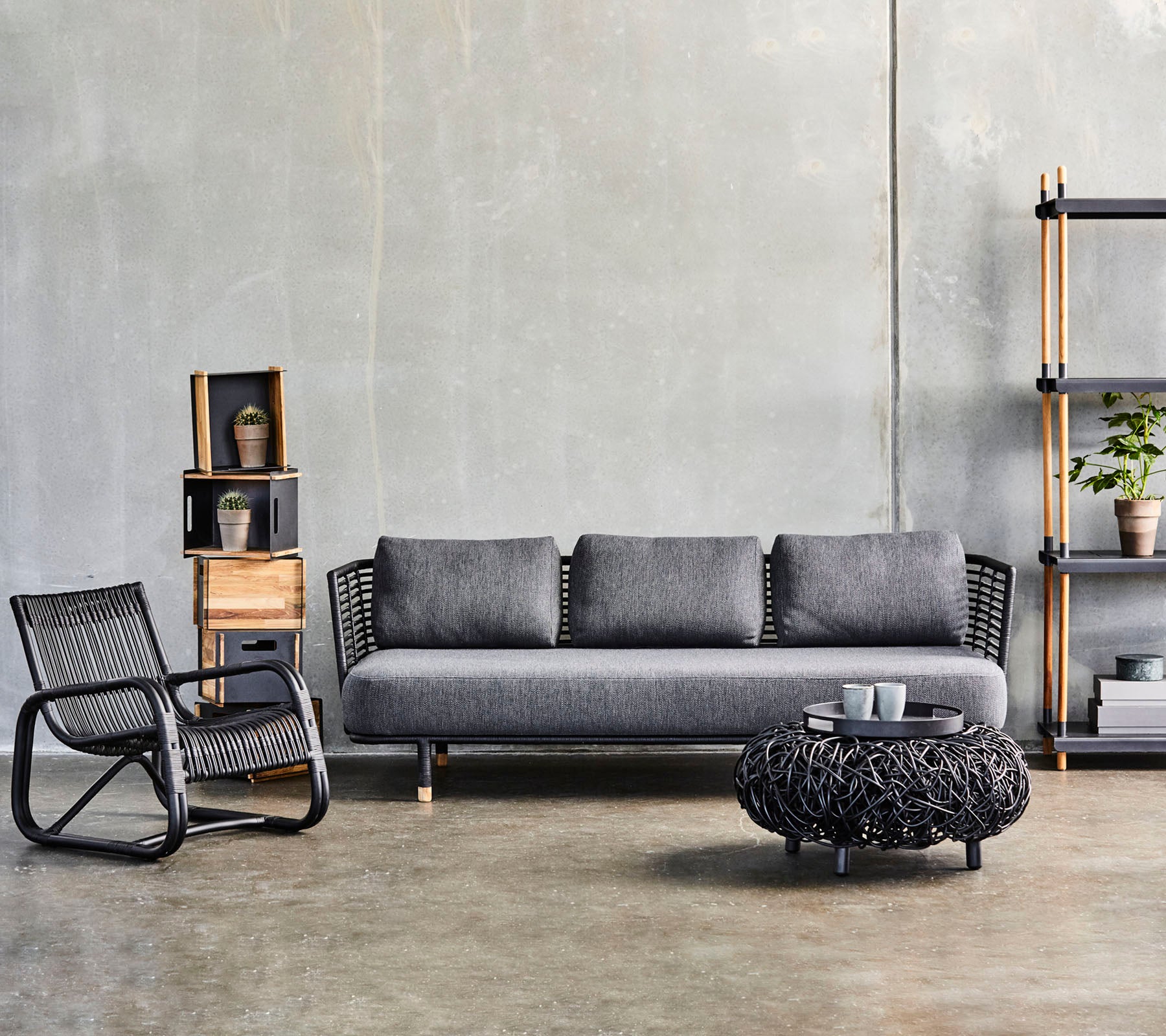 Moderne woonkamerinrichting met een slanke bank, een textuurvol salontafel en een stijlvolle accentstoel, aangevuld met decoratieve planken.