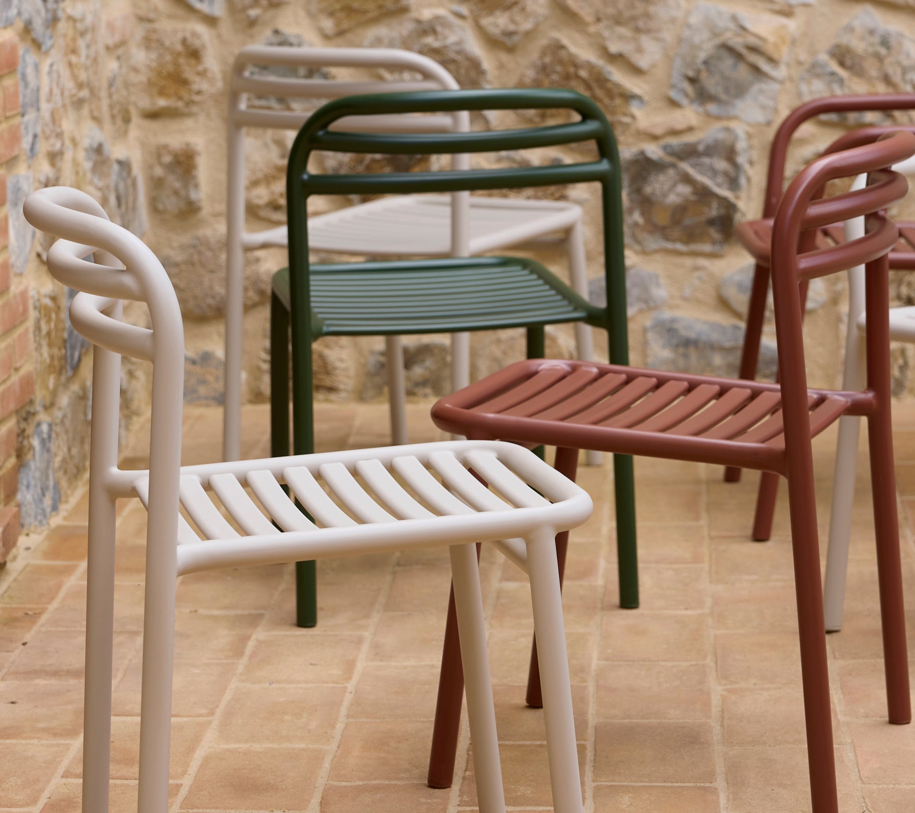 Bliss-stoelen weergegeven in verschillende kleuren, met een modern ontwerp, geslenderde zitting en gebogen armleuningen.