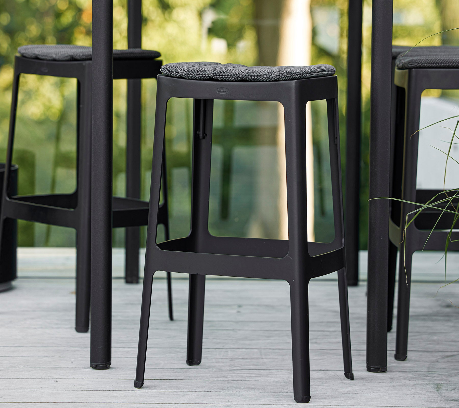 Zwarte barstoelen met een minimalistisch design en gevoerde zittingen, dicht bij elkaar geplaatst en tonen een moderne esthetiek.