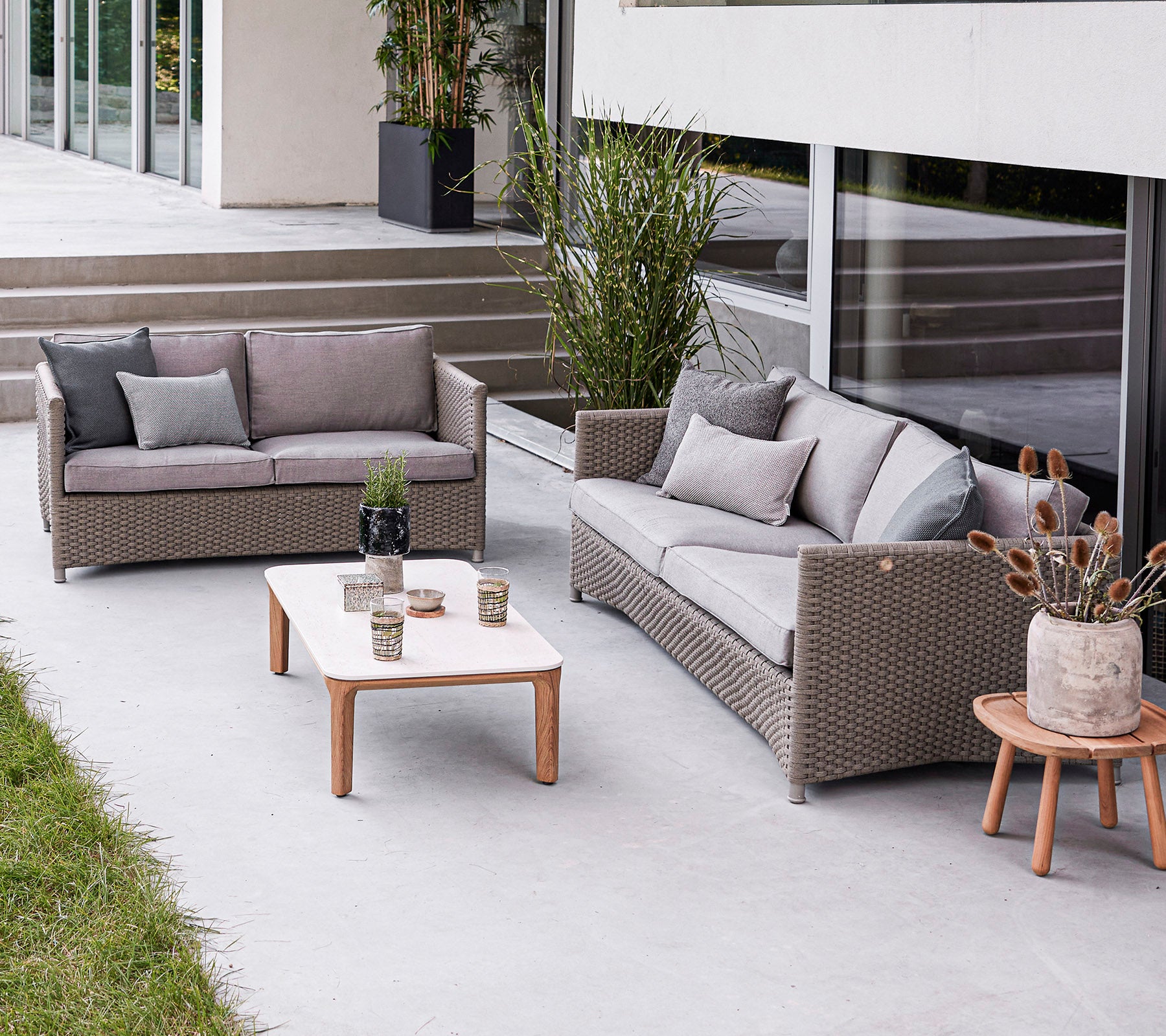 Moderne buitenzit arrangement met een bank, een loveseat en een salontafel met decoratieve elementen. Stijlvolle en uitnodigende sfeer.