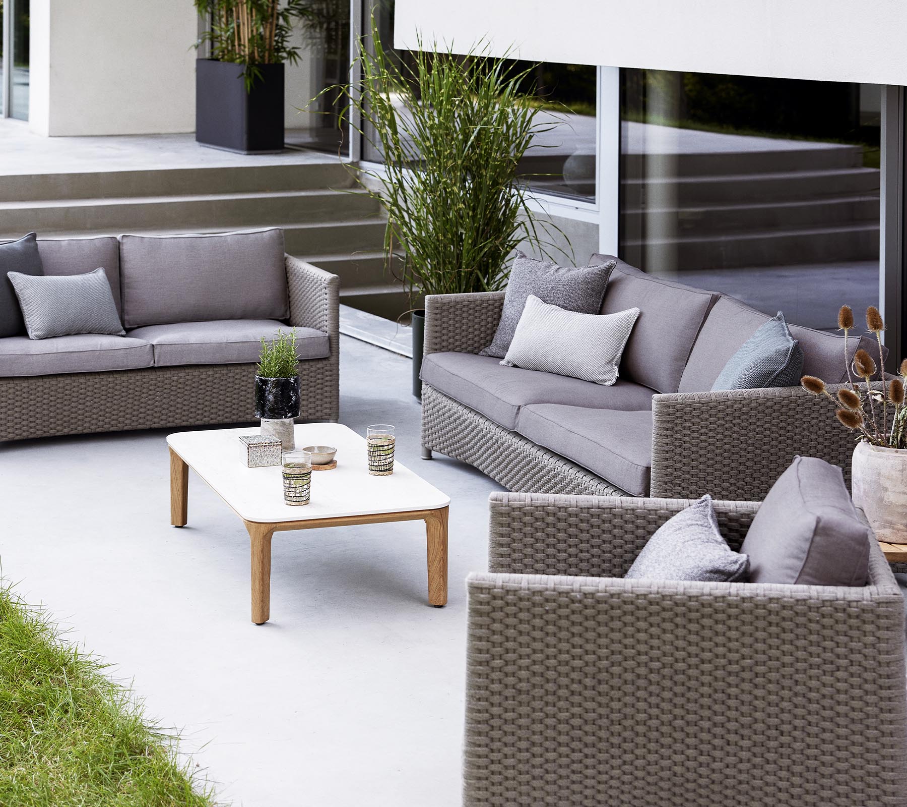 Moderne buitenzitarrangement met een 2-zitbank, een 3-zitbank, loungestoelen en een salontafel met decoratieve items.