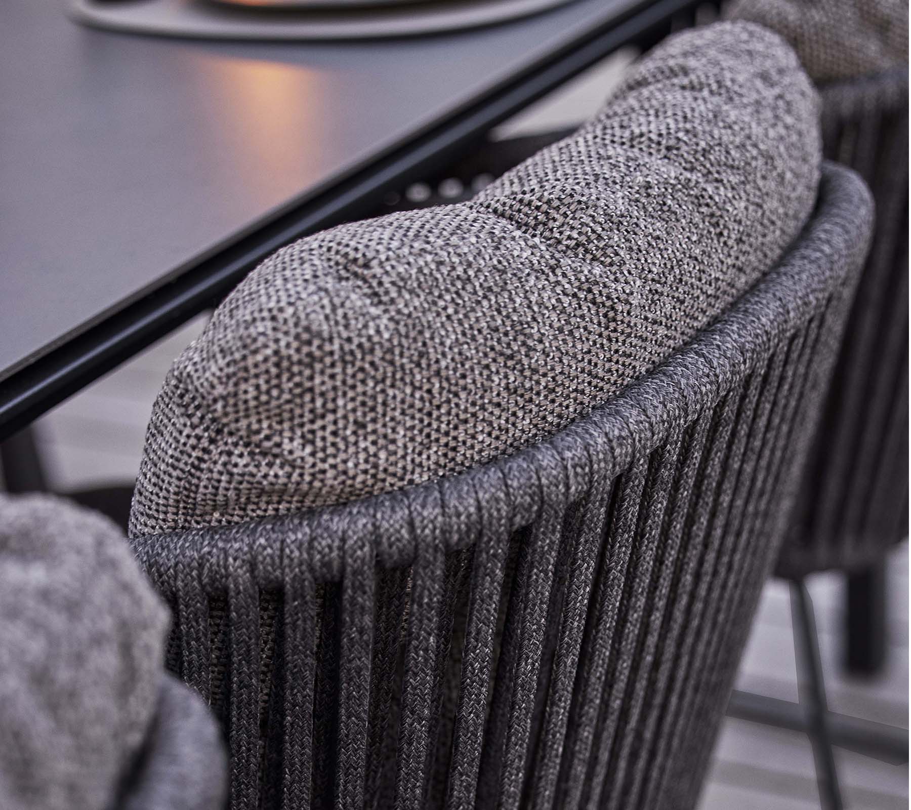 Close-up van een gestructureerde stoelrug met een zachte, gevoerde kussen, met een stijlvolle verticale ribbelontwerp.