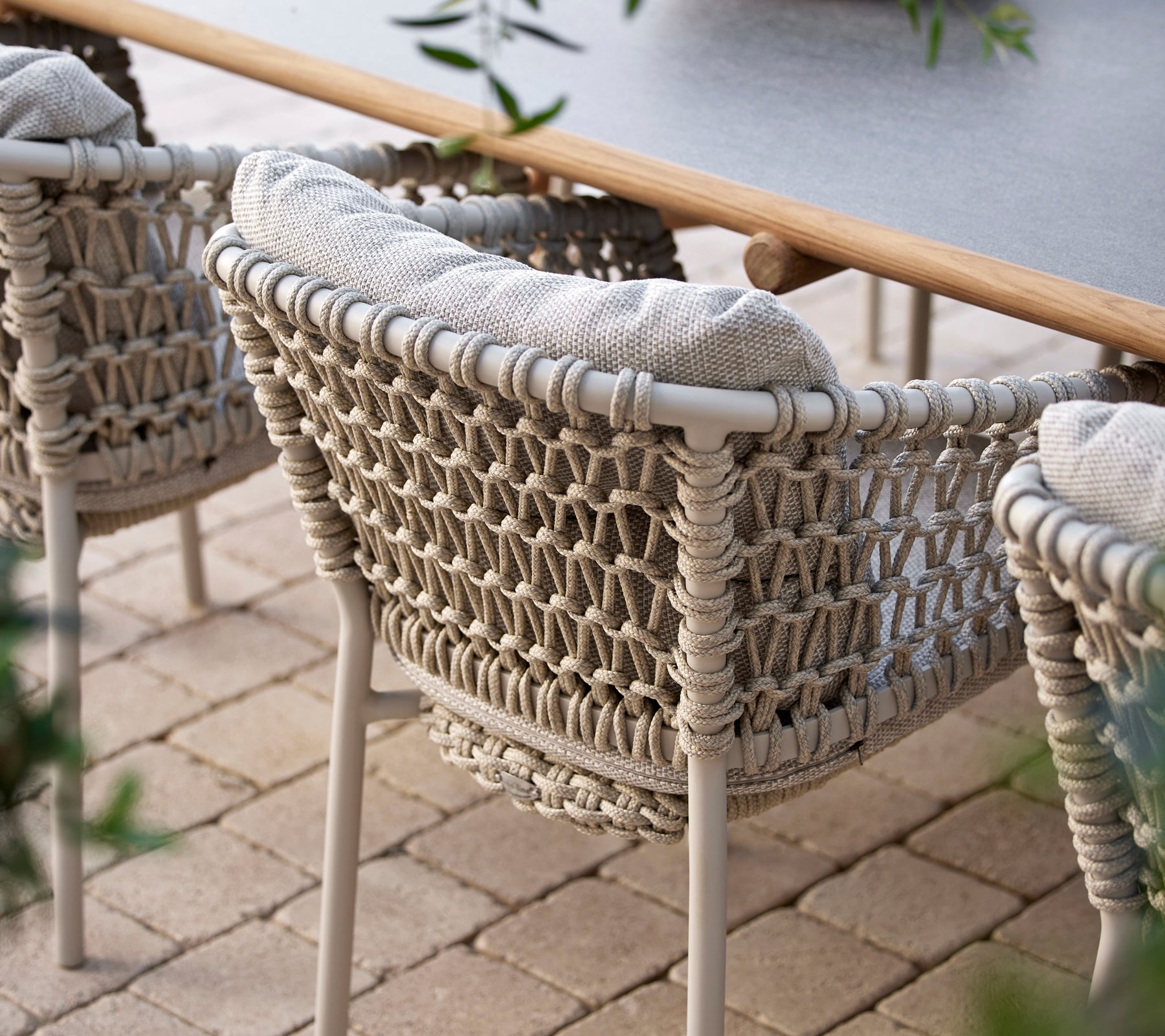 Gezellige eetstoelen met een geweven ontwerp en zachte kussens, perfect voor stijlvolle buiten dineren.