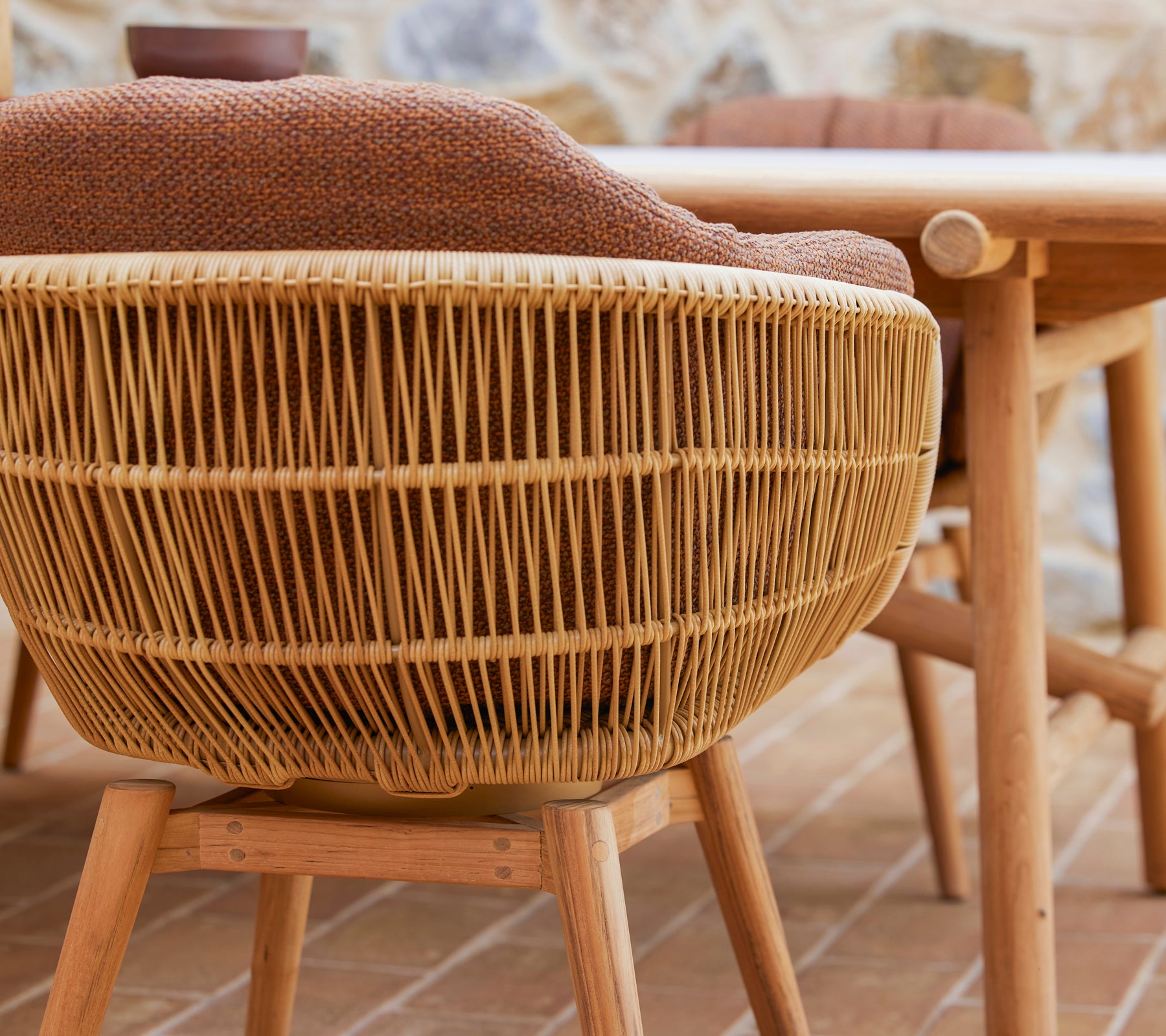 Swivel dining chair with a woven design and teak legs, featuring a comfortable Rice cushion for added style and comfort.