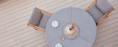 Rond eettafel met comfortabele zitplaatsen, aangevuld met decoratieve borden en een middenstuk. Eenvoudig, elegant ontwerp.