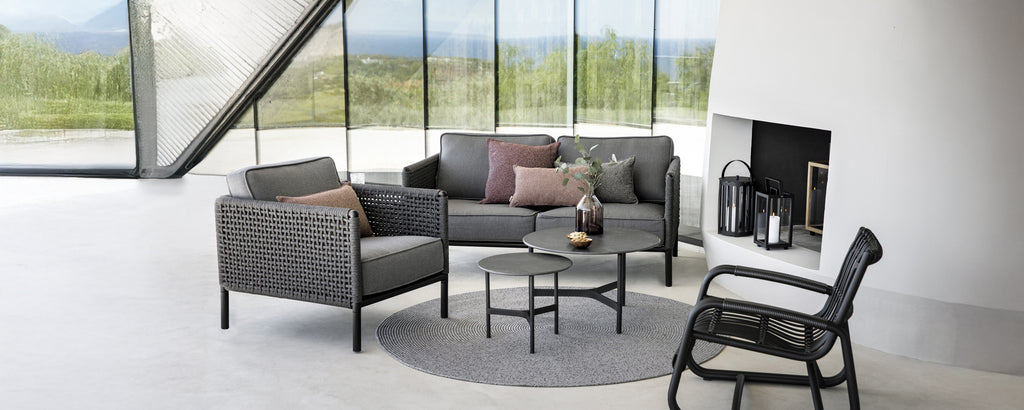 Moderne loungegebied met een grijze bank, zwarte fauteuil en ronde salontafel.