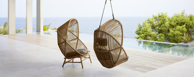 Twee moderne hangstoelen in een hedendaagse setting met uitzicht op water.
