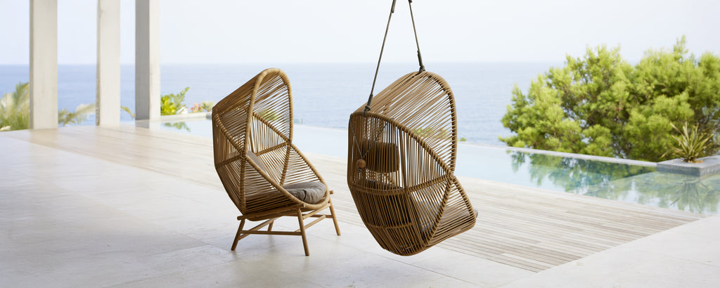 Twee moderne hangstoelen in een hedendaagse setting met uitzicht op water.