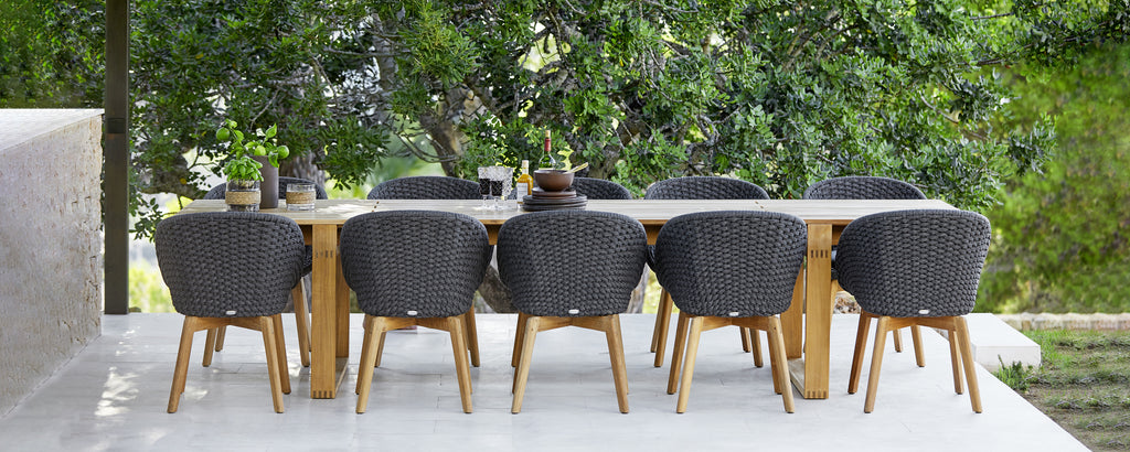 Moderne buitenset met zwarte stoelen en een houten tafel.