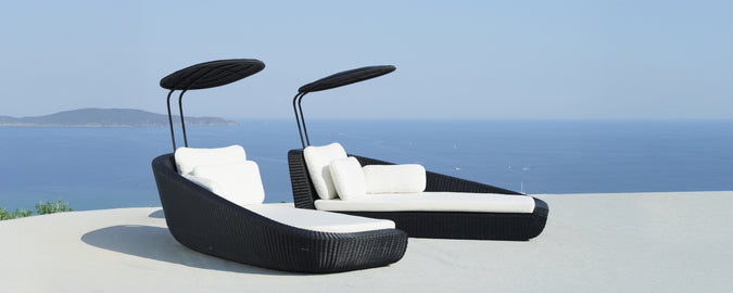 Moderne zwarte loungestoelen met witte kussens met uitzicht op zee.
