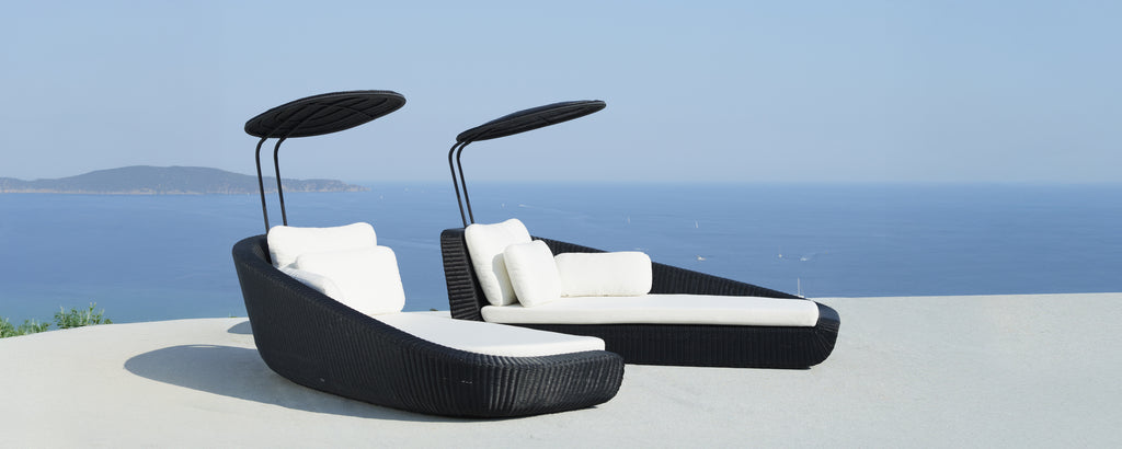 Moderne zwarte loungestoelen met witte kussens met uitzicht op zee.