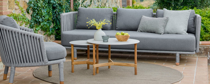 Moderne buiten loungegebied met een grijze bank, grijze stoel en een houten salontafel.