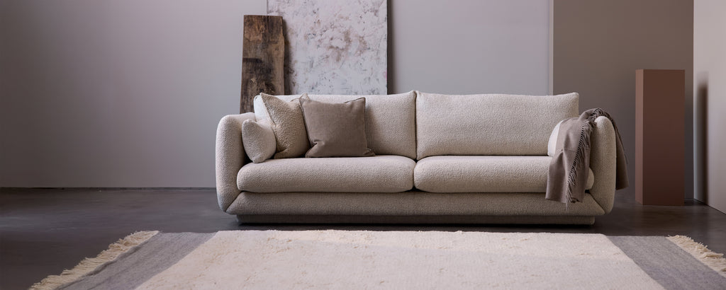 Beige sofa met grijze kussens in een moderne lounge-instelling.