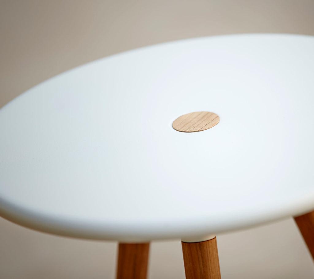 Een stijlvolle kruk met een gladde witte top en een kleine houten accent, ondersteund door houten poten. Ideaal voor moderne decoratie.