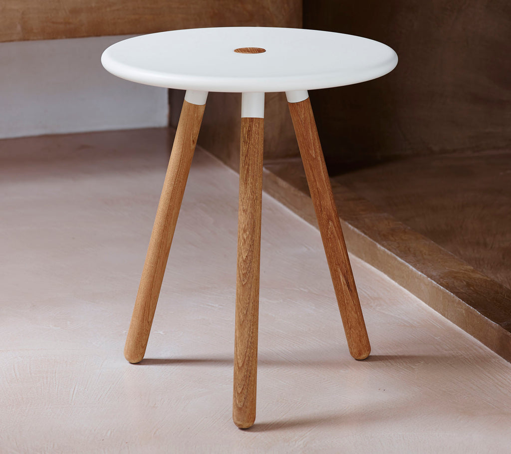 Een moderne ronde tafel met een witte top en natuurlijke houten poten, met een klein gaatje in het midden voor ontwerpinspiratie.