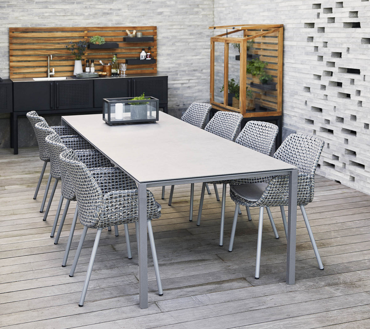 Een stijlvol lange tafel omringd door gevlochten stoelen, met een middenstuk en decoratieve elementen in een moderne setting.