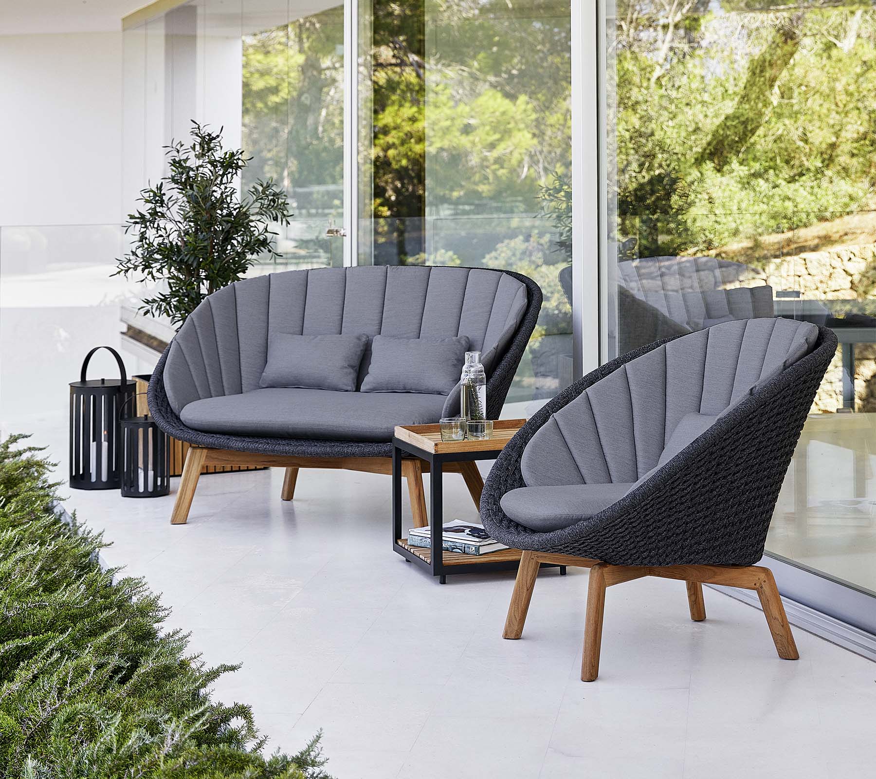 Stijlvolle buitenzit met twee gevoerde stoelen en een loveseat, vergezeld van een kleine tafel en een decoratieve lantaarn.