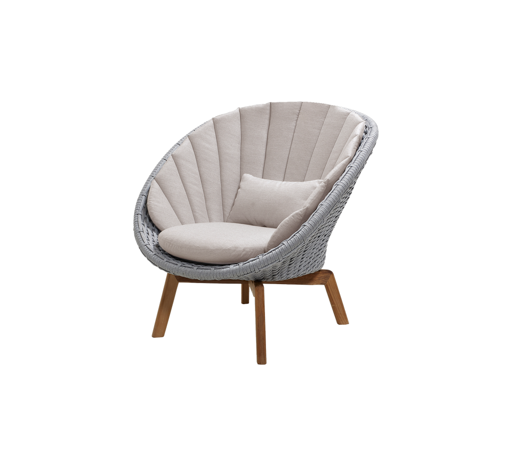 Moderne lichtgrijze stoel met zandkleurige kussen in een lounge-setting.