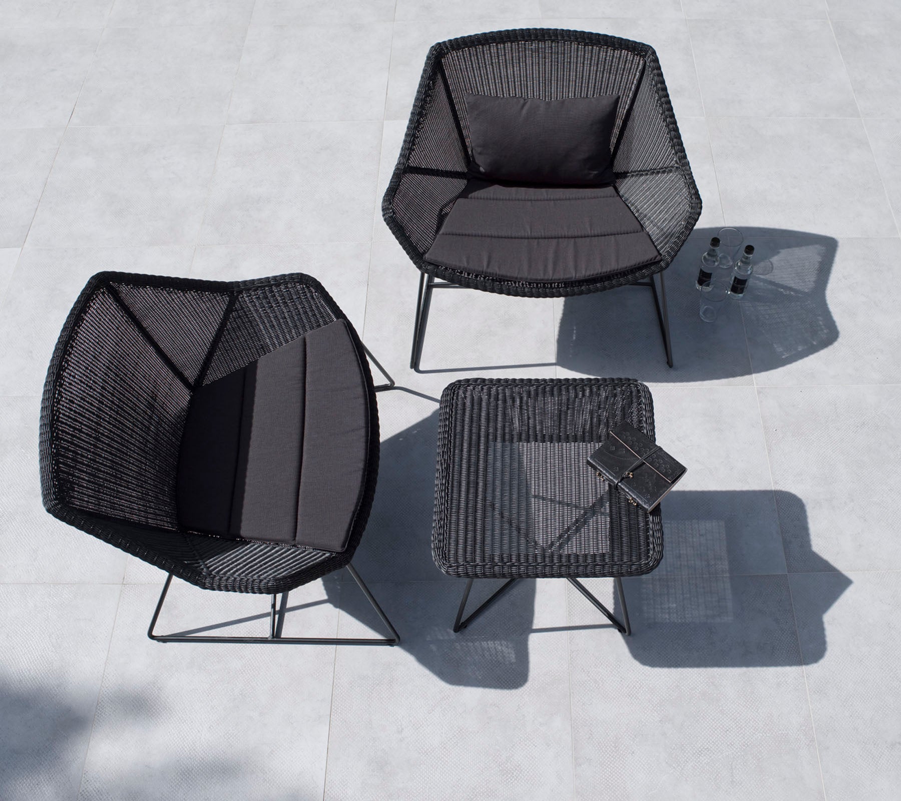 Stijlvolle buitenzitgroep met twee zeshoekige stoelen en een vierkant tafel, allemaal in zwart met een minimalistisch ontwerp.
