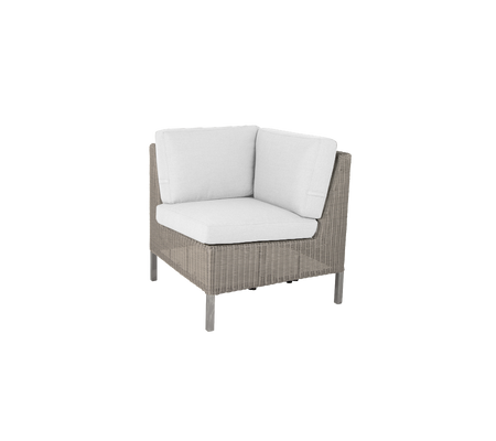 Hoekstoel met een geweven buitenkant en zachte witte kussens, perfect om comfort en stijl aan elke ruimte toe te voegen.