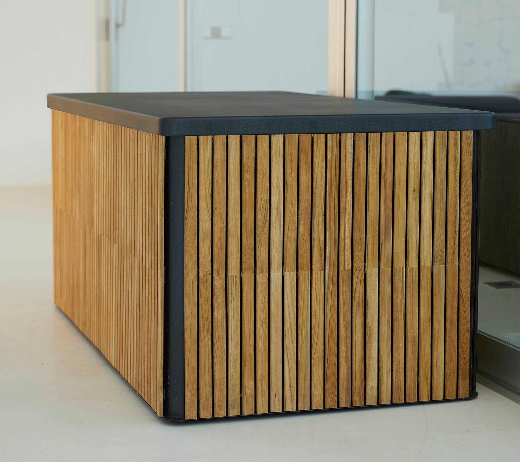 Een moderne houten tafel met verticale latten aan de zijkanten en een slanke donkere bovenkant, die een stijlvol en functioneel ontwerp biedt.