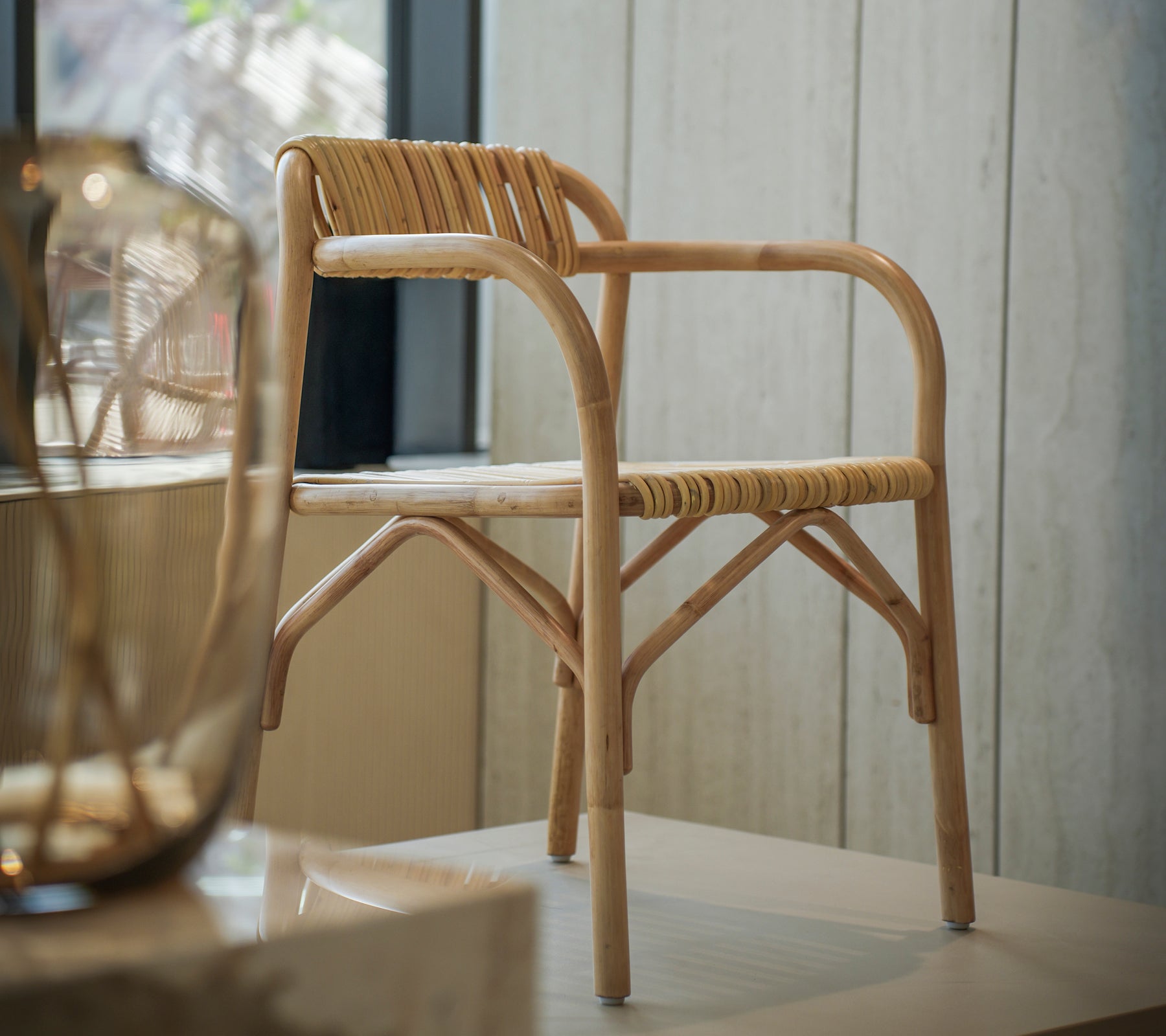 Moderne bamboestoel met een gevlochten zitting in een lichte interieur ruimte.