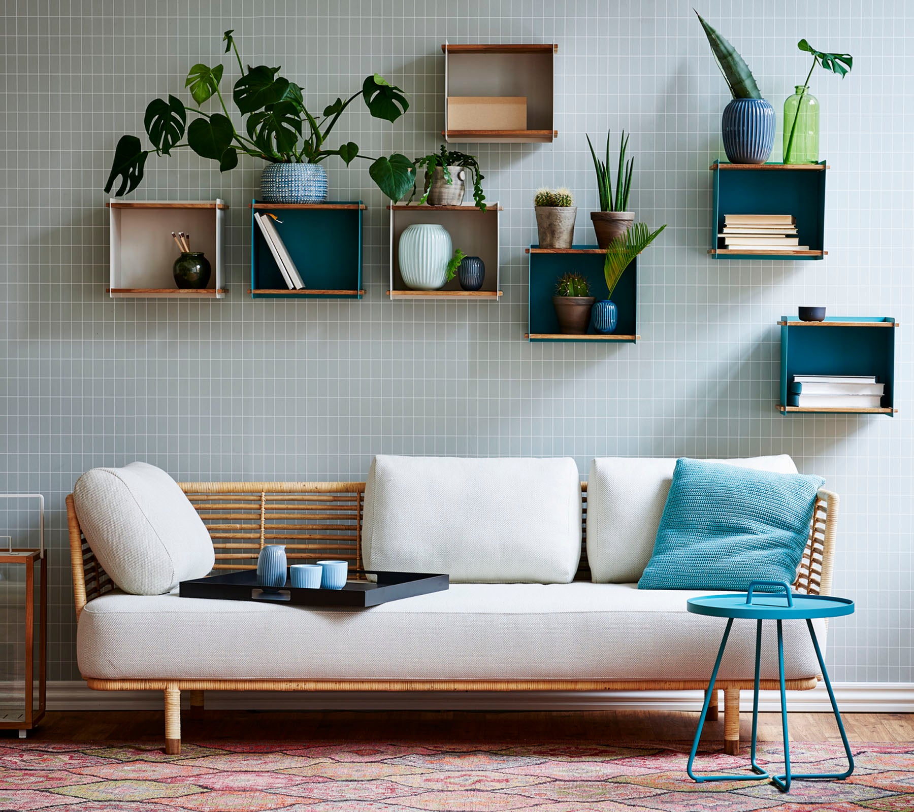 Een stijlvolle bank met een lichte kussen en een kleine tafel, versierd met verschillende potplanten die worden weergegeven op geometrische planken.