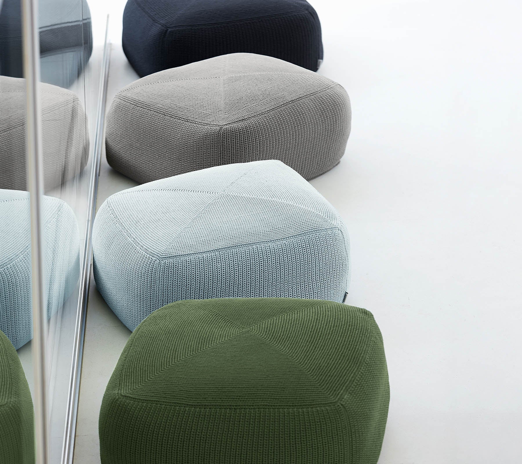 Een verzameling kleurrijke, textuurvolle poufs in verschillende tinten, samen gerangschikt, wat een stijlvolle en moderne uitstraling weerspiegelt.