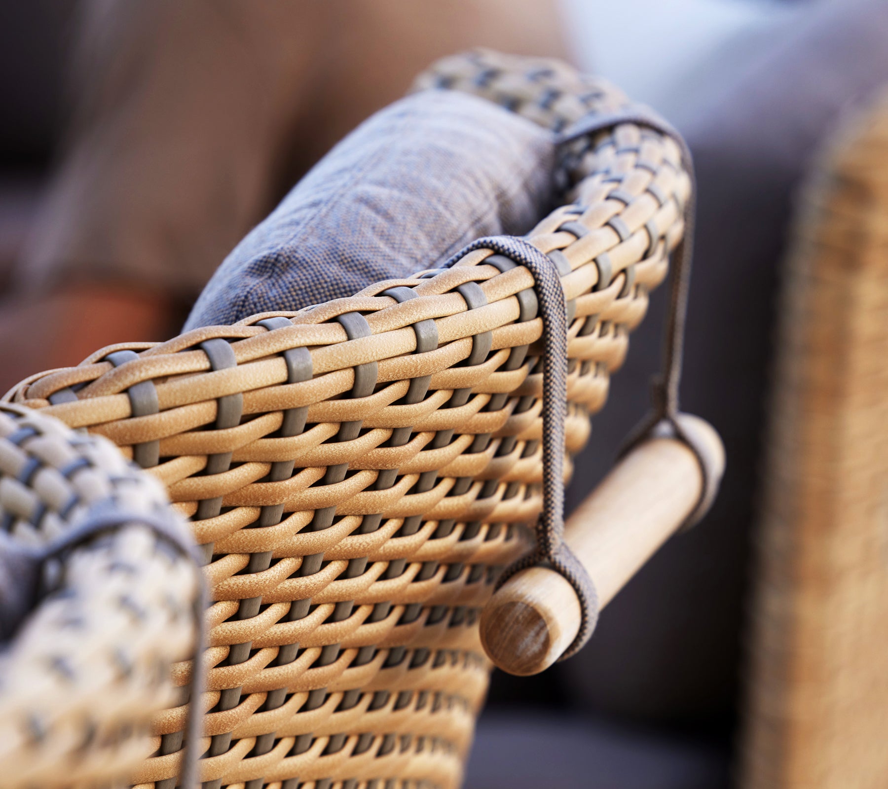 Close-up van een geweven stoelarmleuning met een gewatteerde rugleuning en gebogen neksteun voor extra comfort.