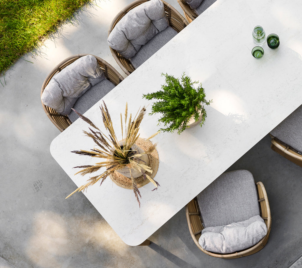 Een moderne eettafel met een gestructureerd oppervlak, omringd door beklede stoelen en versierd met een stijlvolle plantencentral.