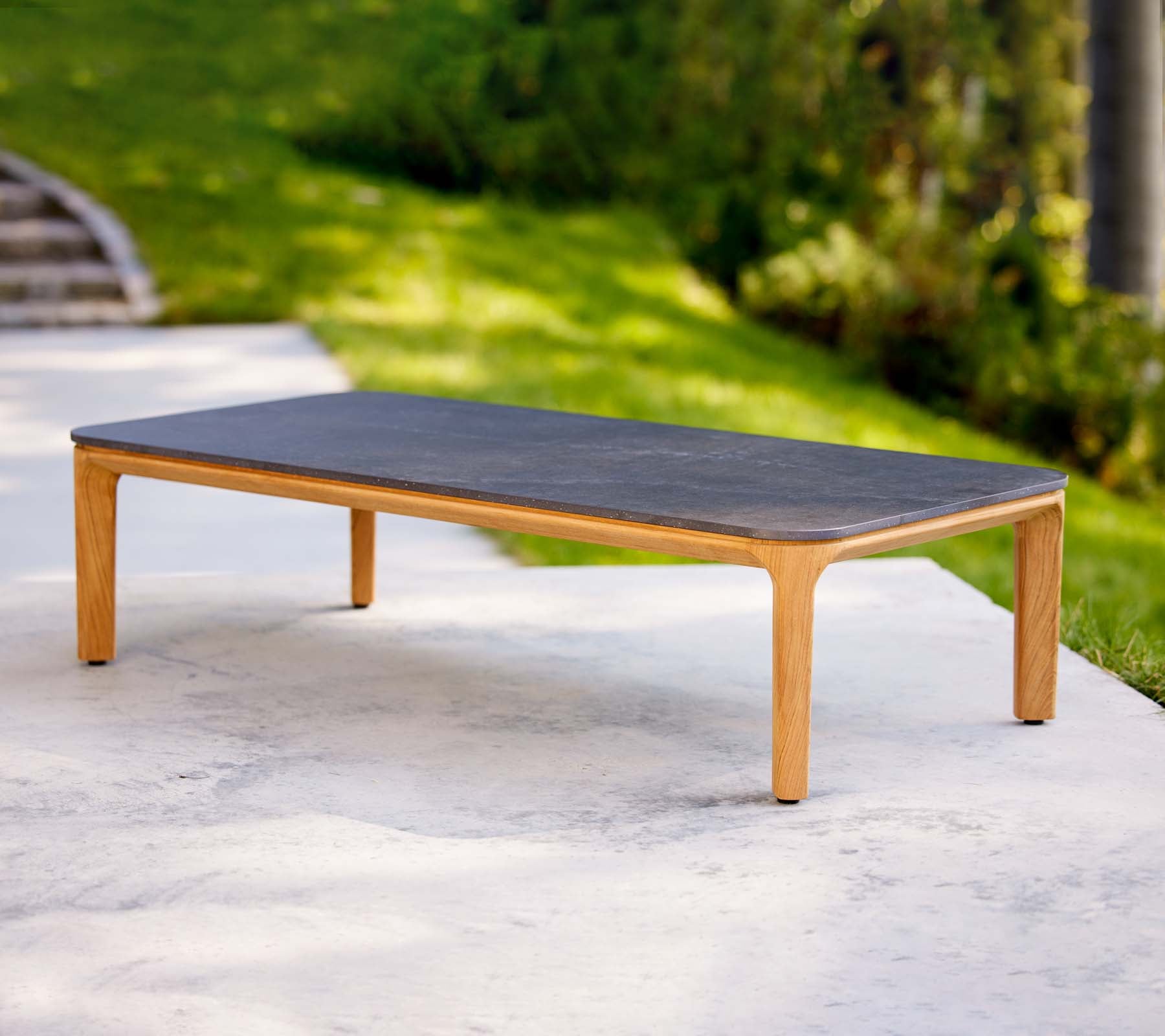 Een strak salontafel met een donkere oppervlakte en lichte houten poten, ideaal voor moderne woonruimtes.