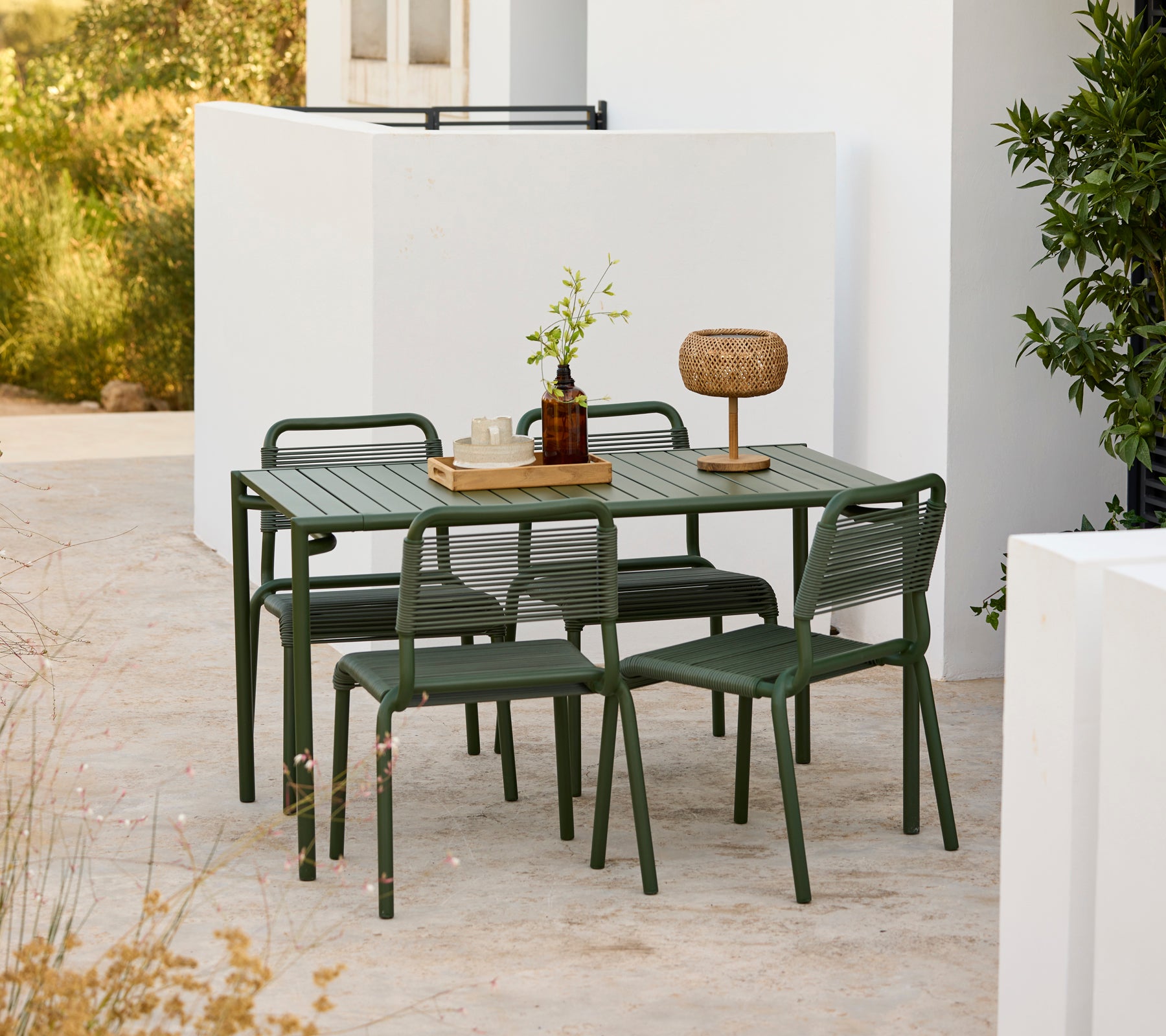 Moderne groene tafel met bijpassende stoelen in een buitenomgeving.
