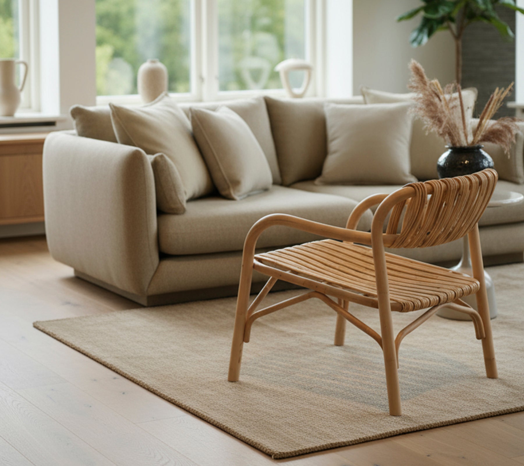 Moderne woonkamer met een beige bank en een gevlochten stoel.