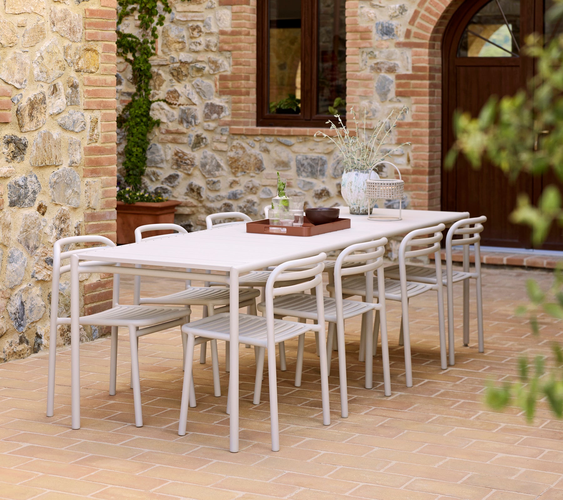 Een moderne eetopstelling met een Bliss-tafel, Bliss-stoelen en een Club-dienblad op een gestructureerd oppervlak.