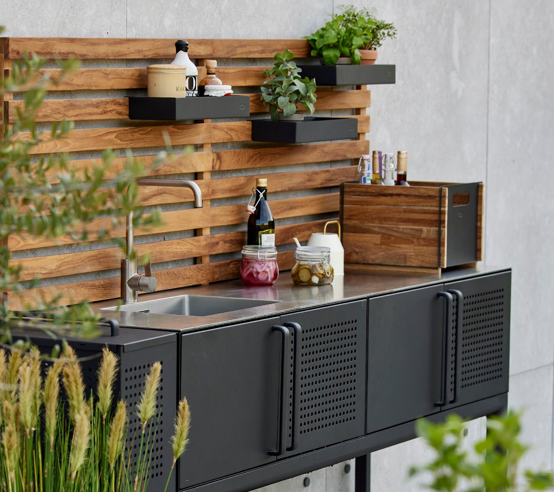 Strakke opbergdoos op een functionele keukenwerkblad met planten en kruiden gepresenteerd op een stijlvolle houten achtergrond.