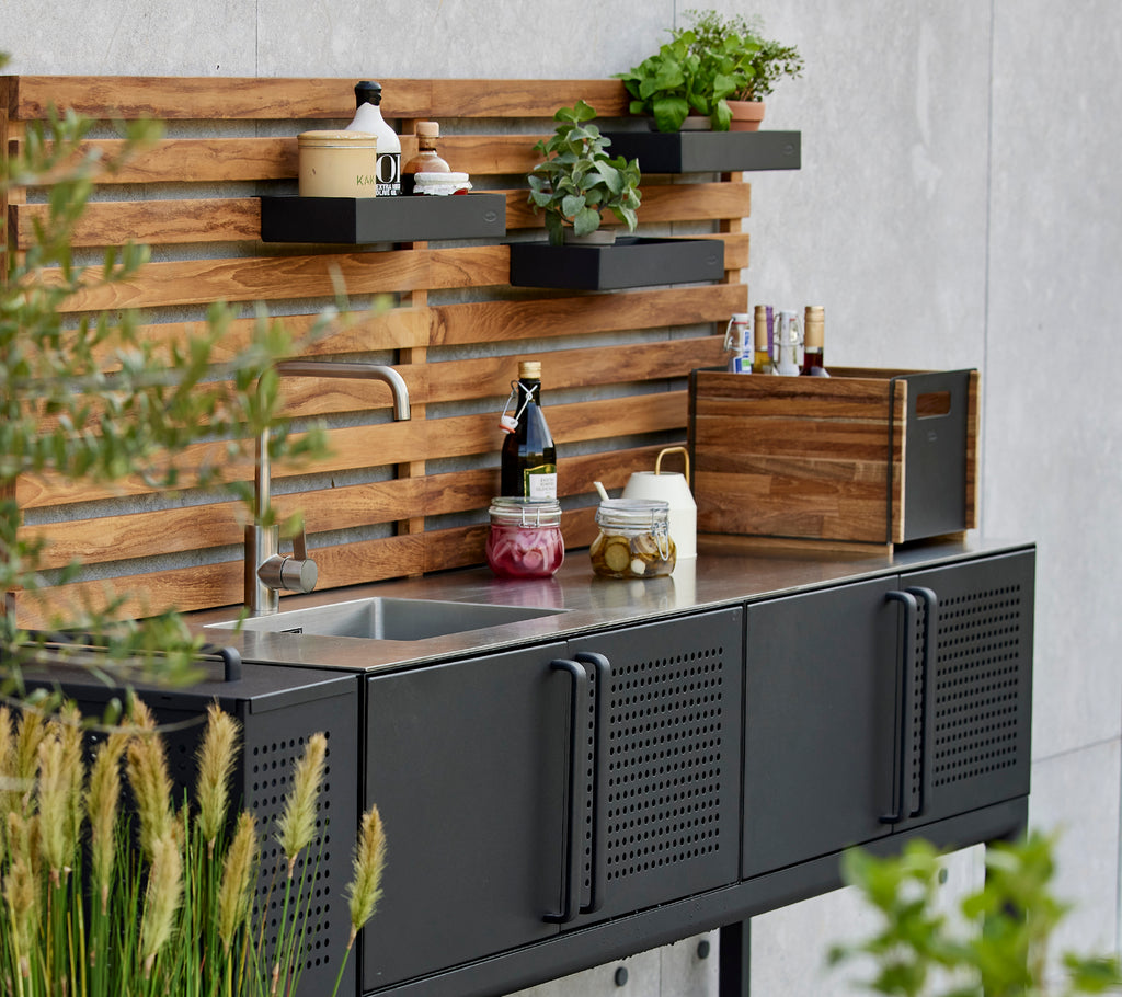 Strakke opbergdoos op een functionele keukenwerkblad met planten en kruiden gepresenteerd op een stijlvolle houten achtergrond.