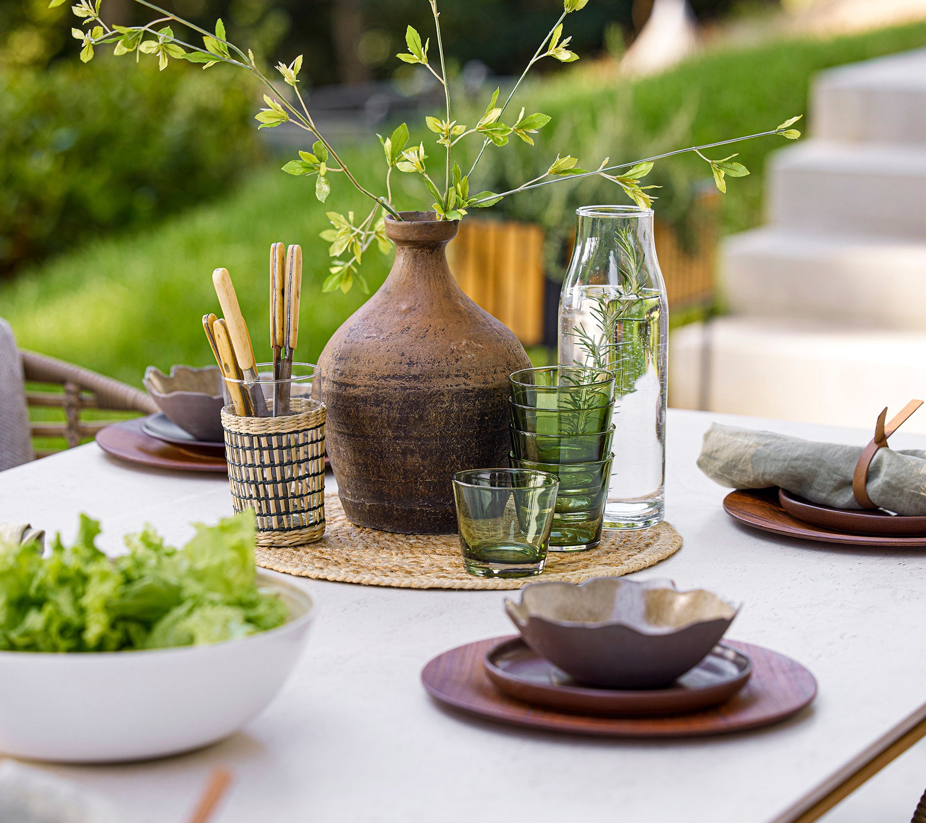 Een prachtig gedekte eettafel met glaswerk, natuurlijke elementen en elegant servies, wat een serene eetomgeving creëert.