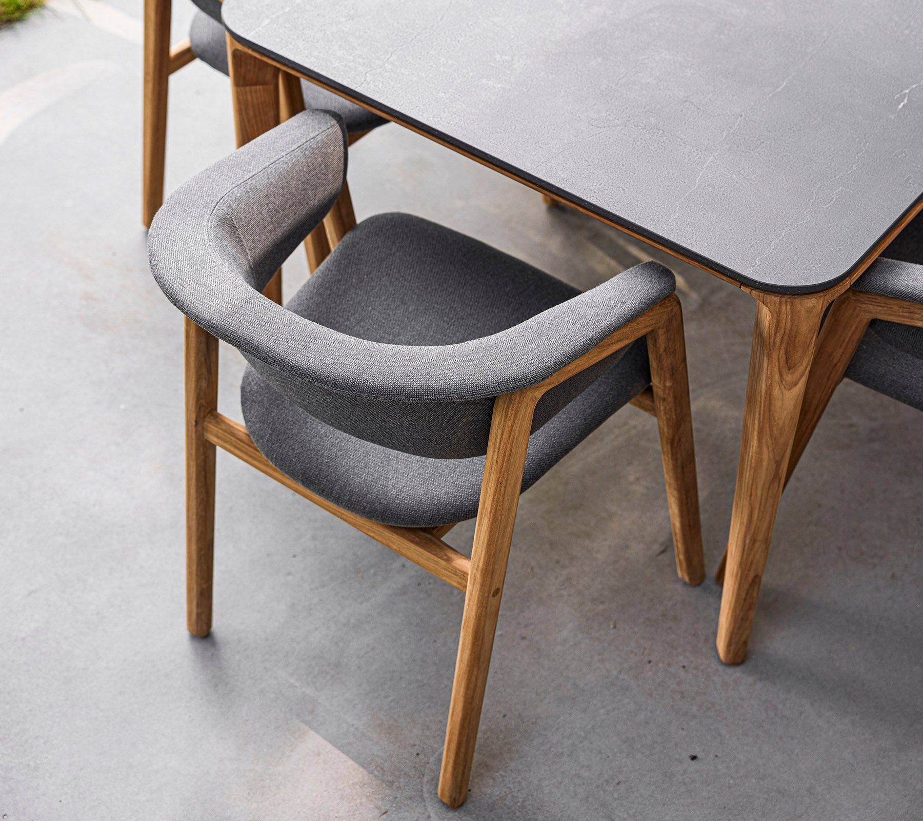 Stijlvolle stoel met een houten frame en zachte grijze bekleding, ontworpen voor comfort en elegantie. Perfect voor moderne eetruimtes.