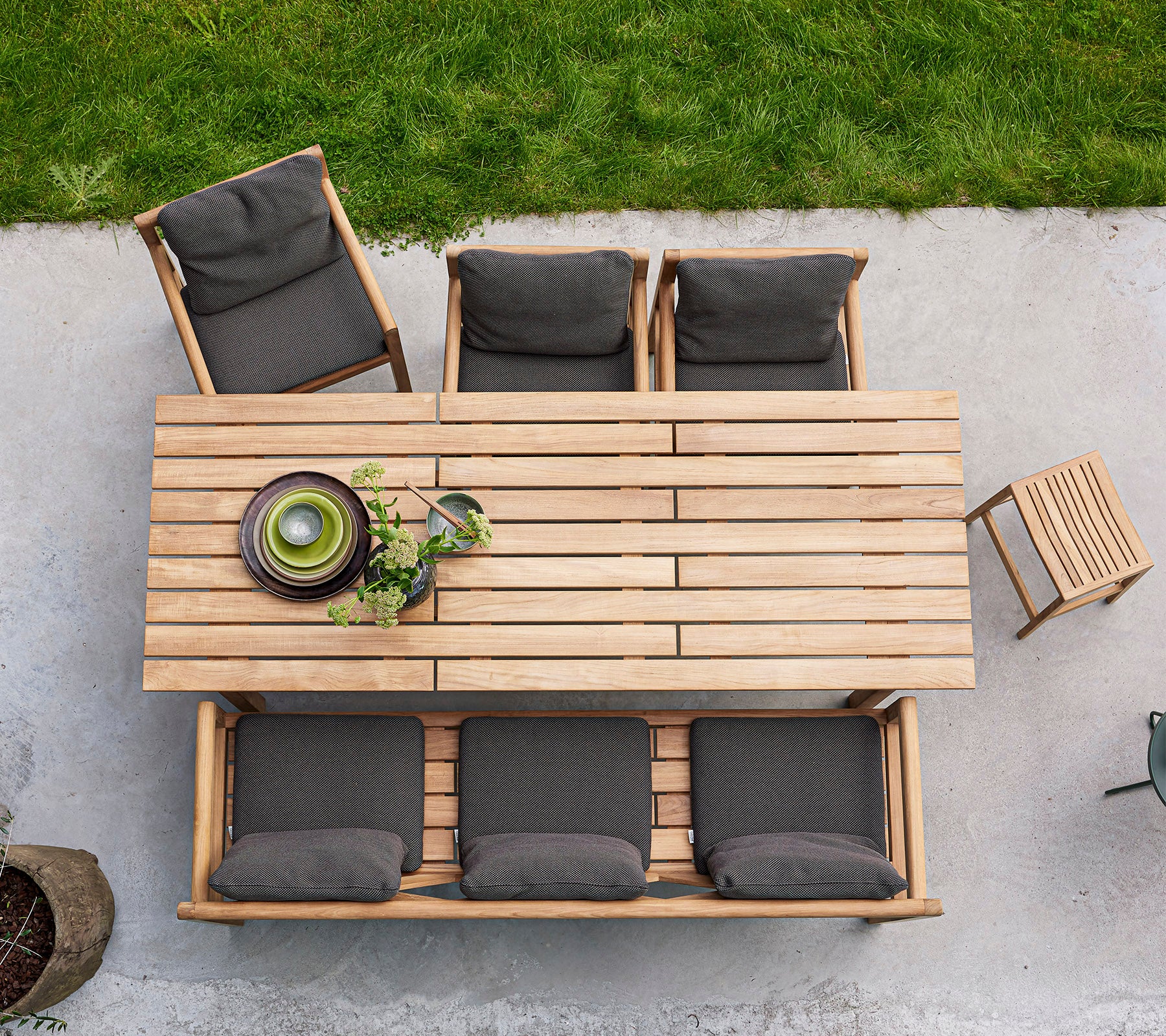 Een houten eettafel met vier gewatteerde stoelen en een schaal met groen, opgesteld voor een uitnodigende bijeenkomst.