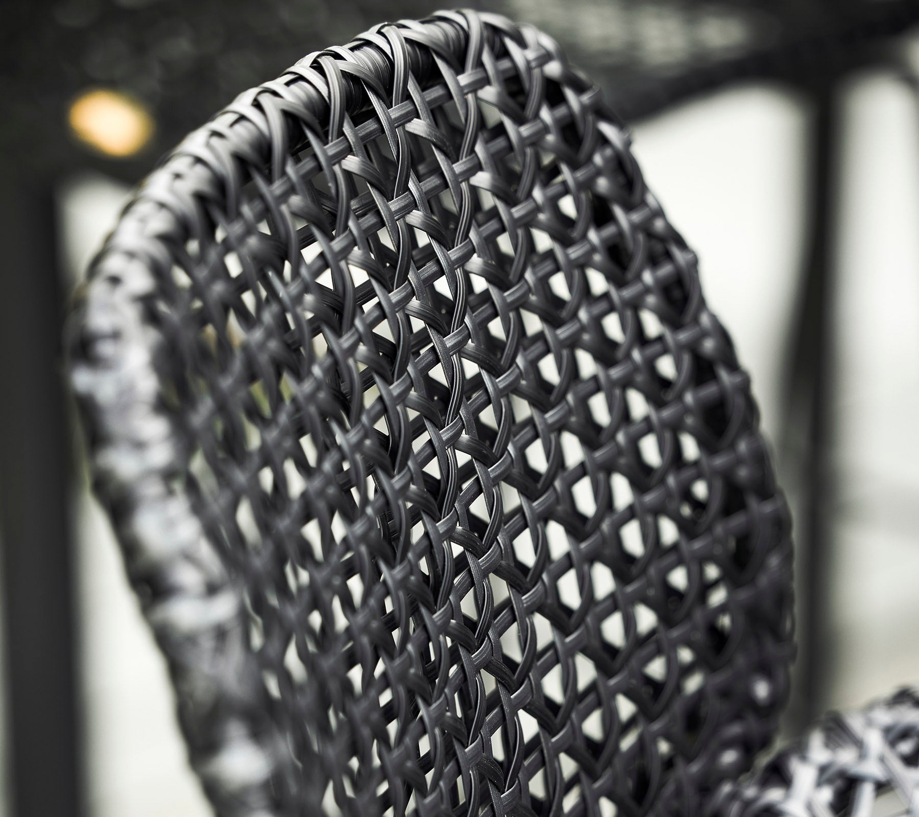 Close-up van een geweven zwarte stoelrugleuning, die ingewikkelde patronen en texturen in het ontwerp toont.