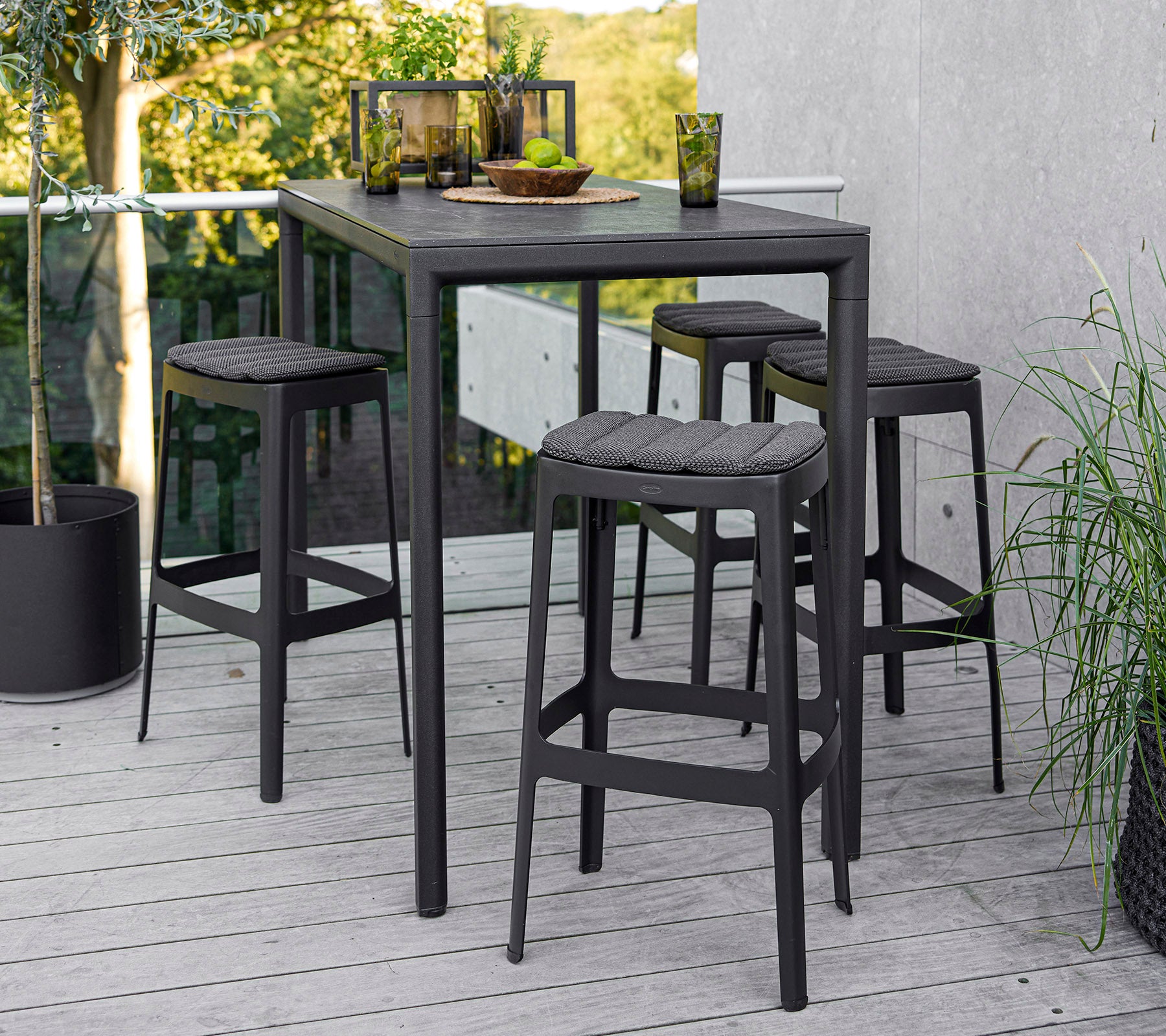 Een moderne tafel met vier bijpassende krukken, met een strak ontwerp en een minimalistische esthetiek, tegen een natuurlijke achtergrond.