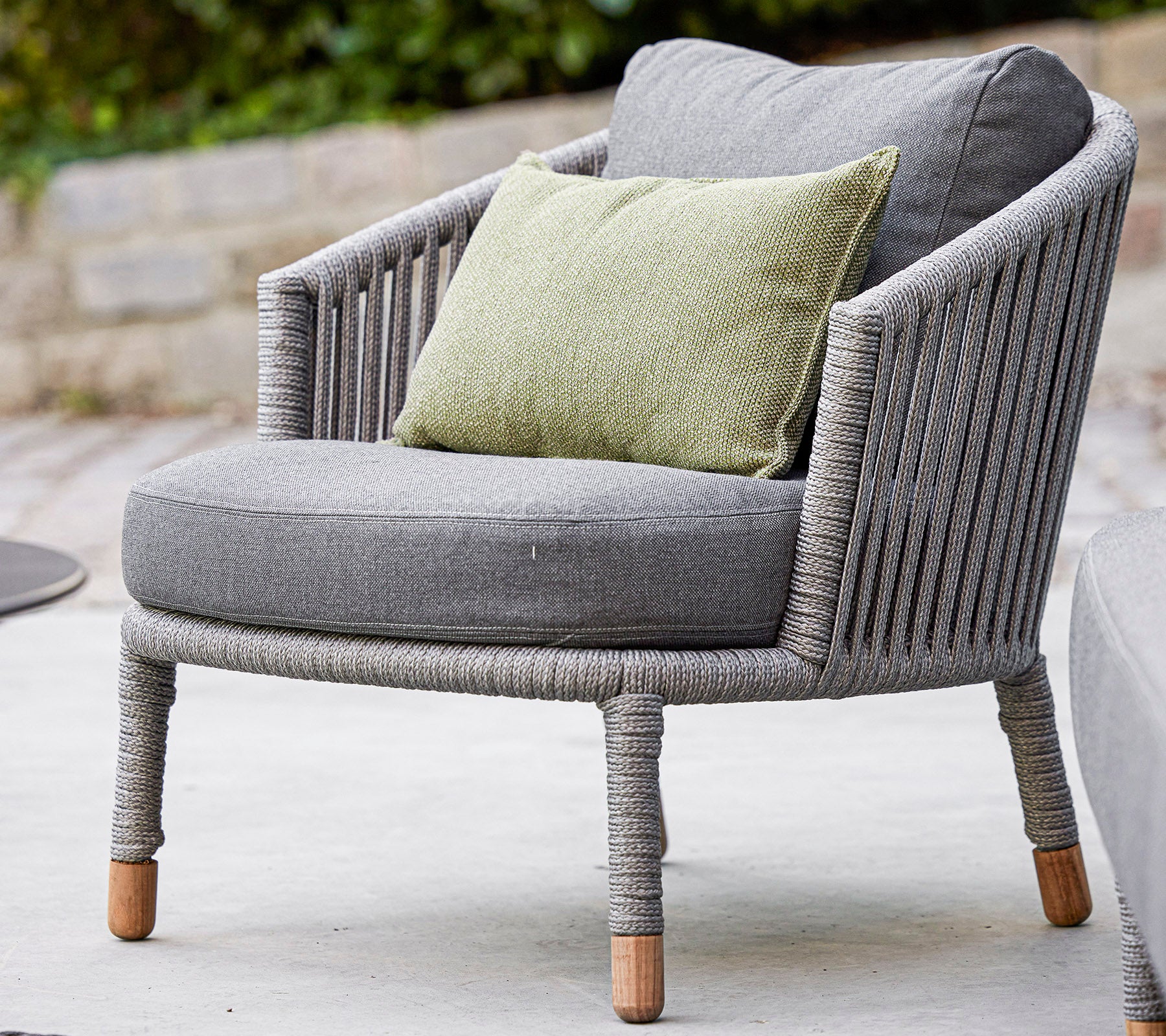 Stijlvolle grijze stoel met een rond ontwerp en een gezellige groene kussen, voorzien van textiel met structuur en natuurlijke houten benen. Perfect voor ontspanning.